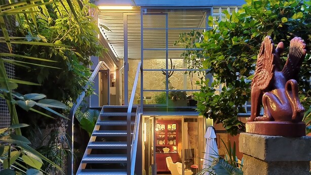 A modern house with a glass facade, a staircase leading to a covered entrance, and a sculpture of a mythical creature. - GARDEN HOUSE in Historical Center, with Garage (Porto)