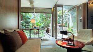 A modern living room with a sofa, a table, and a chair. There is a glass door leading to an outdoor area with plants and a staircase. - GARDEN HOUSE in Historical Center, with Garage (Porto)