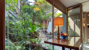 A modern room with a glass wall overlooking a lush garden. There is a table with a bowl of fruit and a lamp. - GARDEN HOUSE in Historical Center, with Garage (Porto)