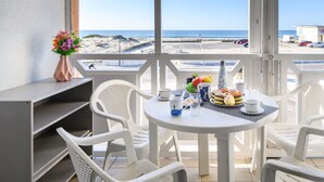 A balcony with a table set for breakfast, white chairs, and a vase of flowers. - Beautiful apartment for 4 people with WIFI, TV, balcony and pets allowed (Mimizan)