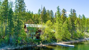 A cabin surrounded by dense forest, a dock extending into a calm lake, and a clear sky. - Lakefront Cabin on Blanchard Lake- 5 minutes to Downtown Whitefish (Whitefish)
