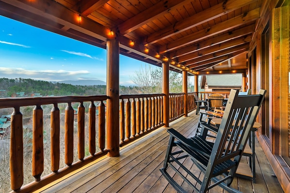 A wooden deck with a railing, outdoor seating, and a view of the landscape.