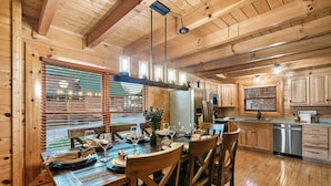 Un interior de madera con una mesa de comedor dispuesta para seis personas, un refrigerador y armarios de madera.