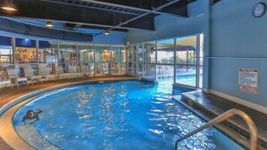 An indoor swimming pool with clear water, surrounded by lounge chairs and a glass wall. - Beautiful Updated Pelican Beach Unit!!! (Destin)