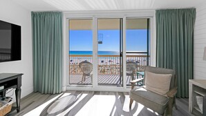 A balcony with a view of the beach, a sofa, and a TV. - Beautiful Updated Pelican Beach Unit!!! (Destin)