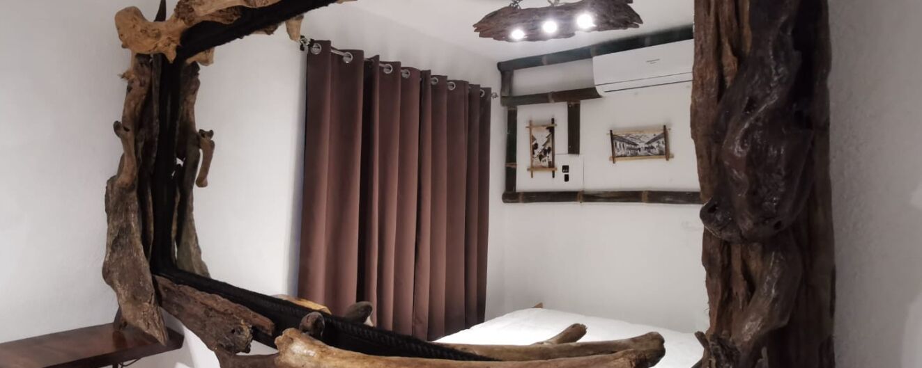 Ein Badezimmer mit einem rustikalen Holzspiegel, einem weißen Waschbecken und einem braunen Vorhang.
