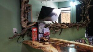 A room with a unique wooden bar counter, a television mounted on a wall, and a mirror with a natural design. - Casa Zury Playa (QUEPOS)