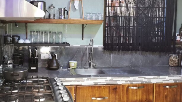 A kitchen with a gas stove, coffee maker, and various kitchen utensils. - Casa Zury Playa (QUEPOS)
