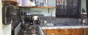 A kitchen with a gas stove, coffee maker, and various kitchen utensils. - Casa Zury Playa (QUEPOS)