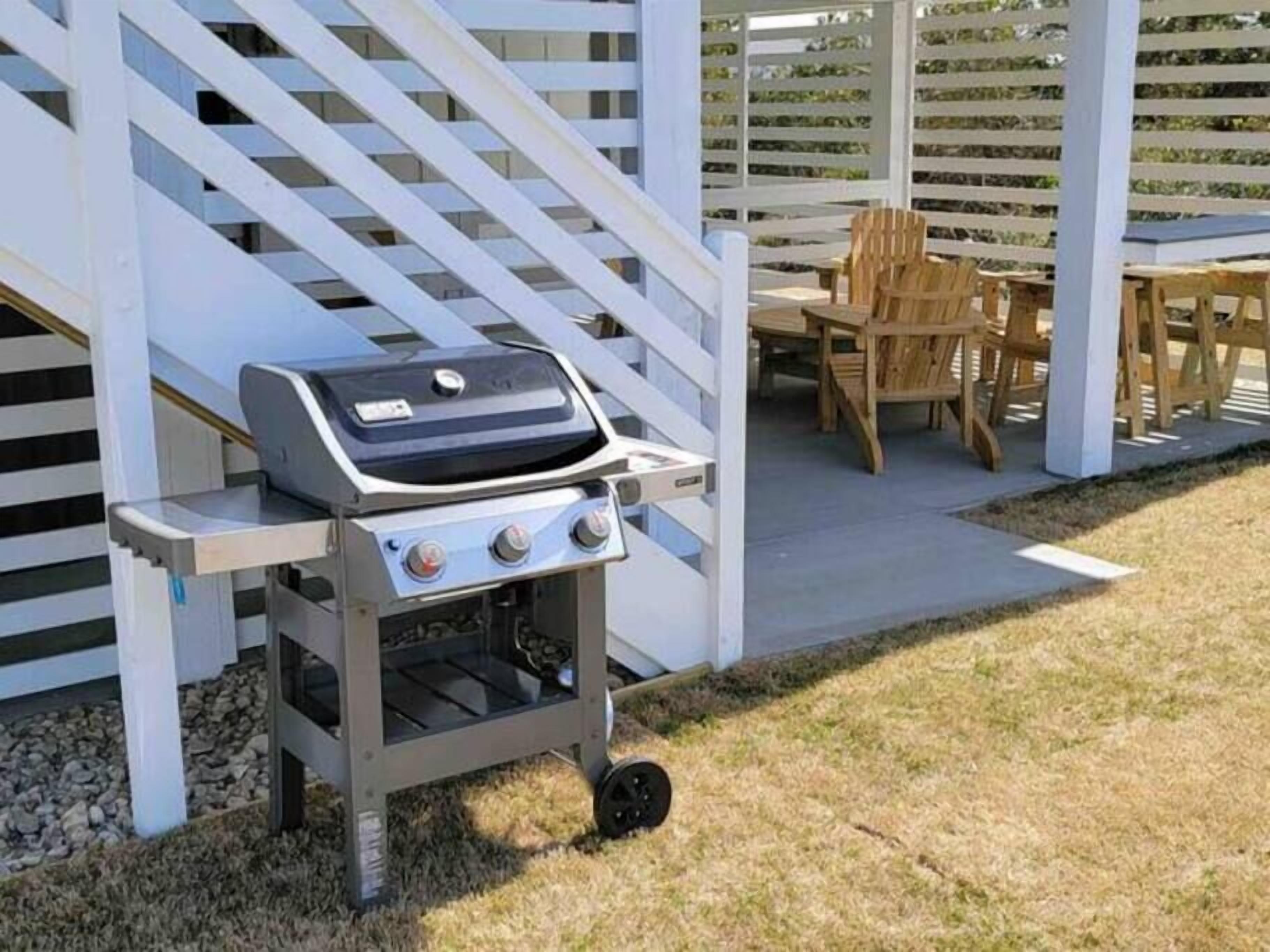 Ein tragbarer Grill mit Bedienfeld, auf einer Wiese neben einem weißen Zaun platziert.