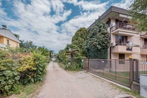 Une rue résidentielle bordée de maisons, avec un chemin de gravier et une clôture fermée par un portail.