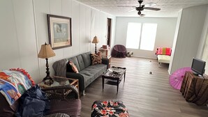 Een ruime woonkamer met een bank, fauteuils, een salontafel en een televisie.