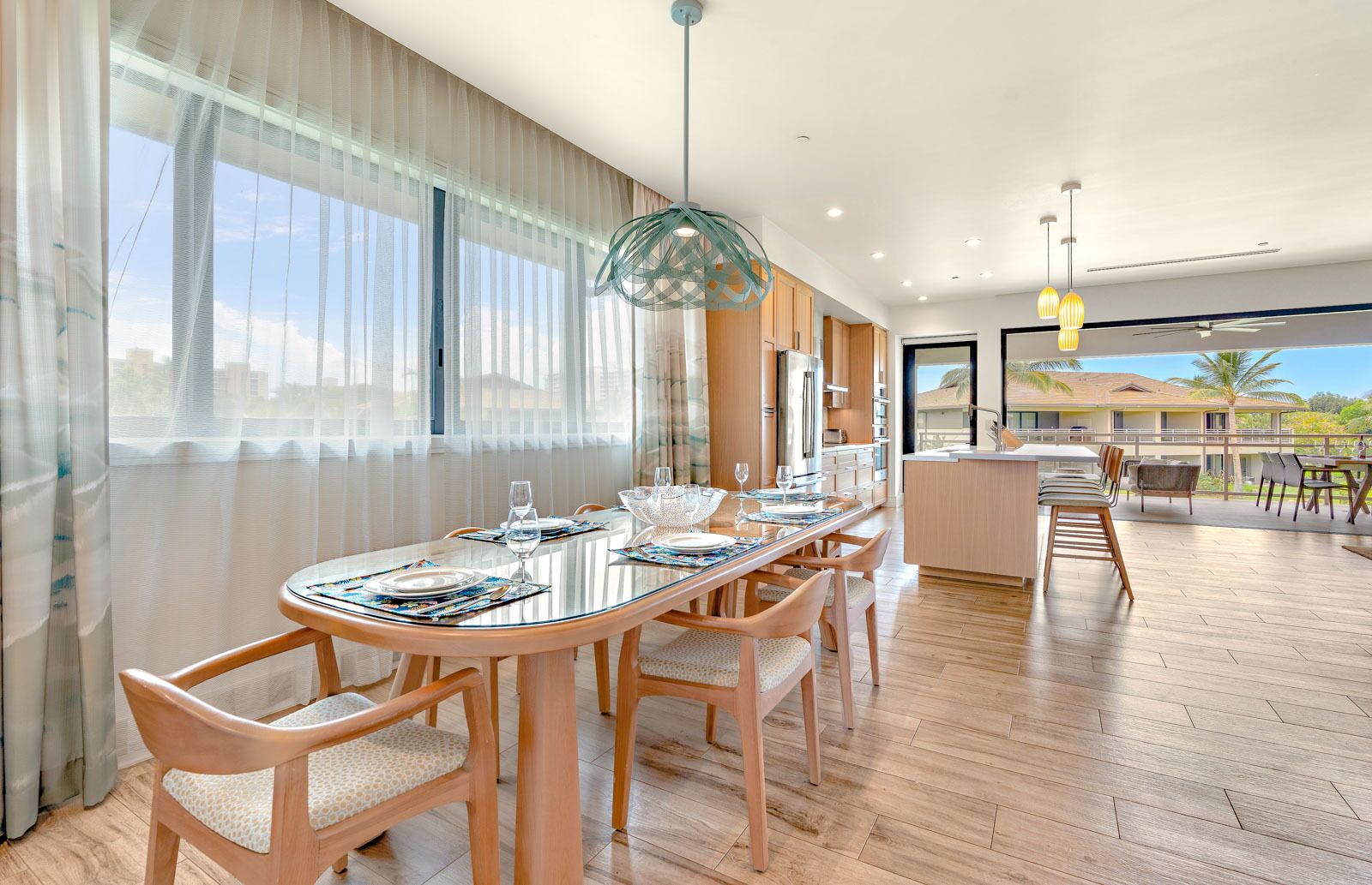 A modern dining area with a glass table, wooden chairs, and a view of the cityscape through large windows.