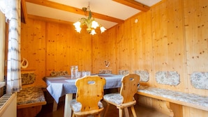 A wooden cabin interior with a dining table, two chairs, a bench, and a hanging light fixture. - Beautiful  villa for 5 people with WIFI, TV and terrace (Oetz)