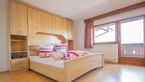 A bedroom with a wooden bed, built-in wardrobe, and a window with a view. - Beautiful  villa for 5 people with WIFI, TV and terrace (Oetz)