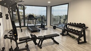 Ett gym med träningsredskap, ett löpband och en bänk.