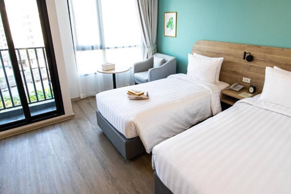 Habitación de hotel con dos camas, una mesita, una silla y ventana con vistas.