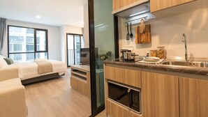 A modern apartment with a kitchen, dining area, and a living room with a sofa and TV.