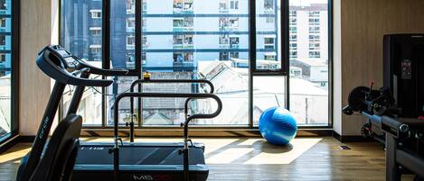 A gym with a treadmill, exercise ball, and weights.