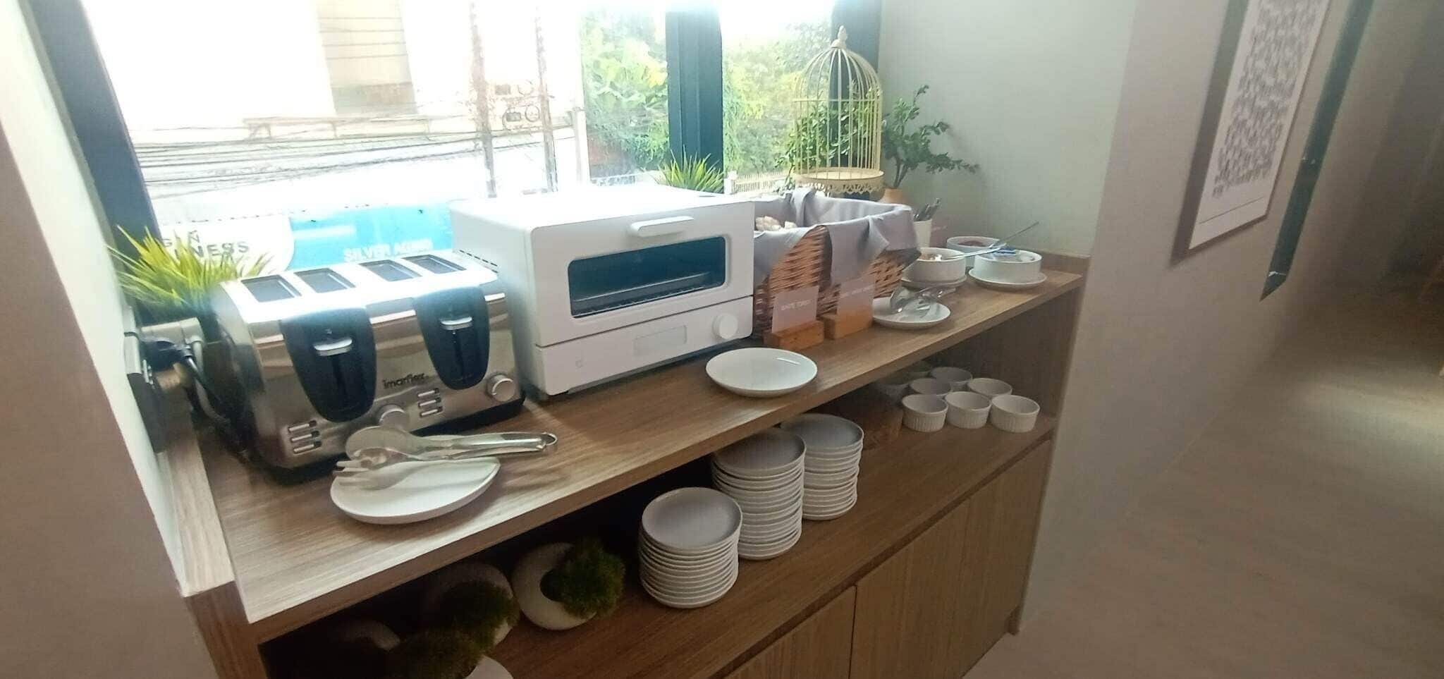 A breakfast bar with a coffee maker, toaster, and stacked plates.