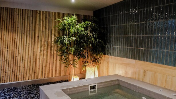 A spa area with a hot tub, bamboo wall, and a tiled wall.
