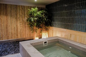 Un espace bien-être comprenant un jacuzzi, un mur en bambou et un mur recouvert de carreaux.