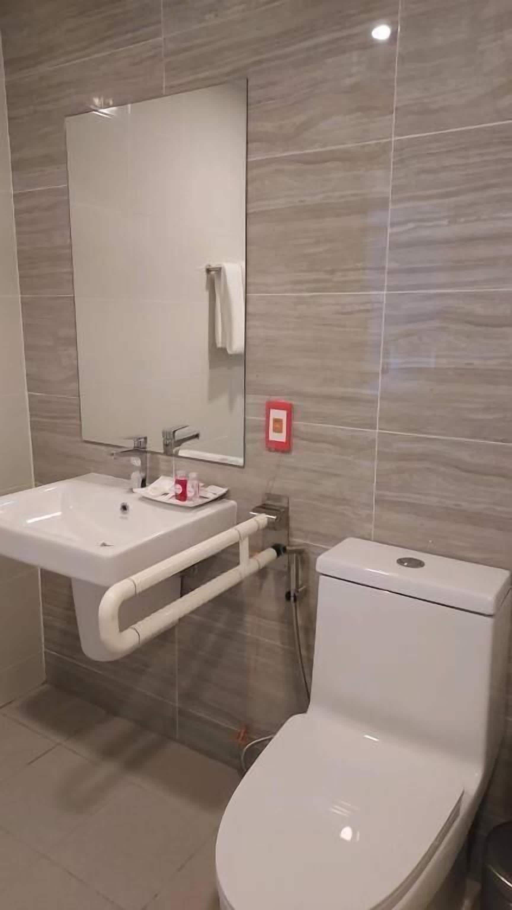 Een badkamer met een wit wastafel, spiegel en toilet.