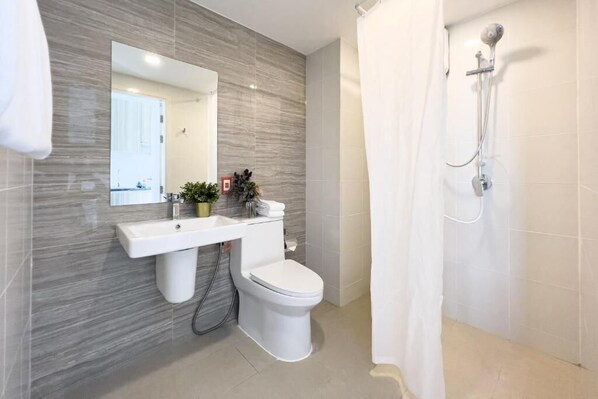 Un baño moderno con salpicadero de mármol, un lavabo blanco, un inodoro y una ducha con cortina.