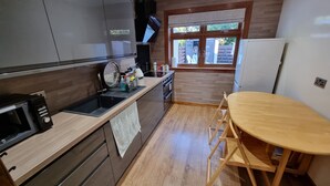 A compact kitchen with a microwave, sink, and wooden table. - Captivating 1-Bed Apartment in Edinburgh (Edinburgh)