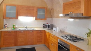 Una cocina con muebles de madera, un microondas, una estufa a gas y un lavamanos.