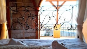 Una cama con un edredón estampado, una reja de hierro forjado y una pared de piedra.