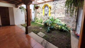 Une cour intérieure avec un mur en pierre, un plafond en bois et des plantes suspendues.