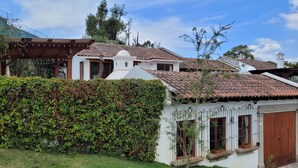 Un bâtiment blanc avec un toit en tuiles, une clôture en bois et un jardin bien entretenu.