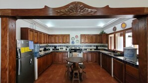Une cuisine avec des meubles en bois, un îlot central doté de tabourets, un réfrigérateur, un four à micro-ondes et une cuisinière.