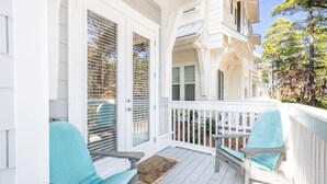 A covered porch with two light blue chairs, a wooden bench, and a white railing. - Cozy 3bed townhome close to beach/step from Hub (Rosemary Beach)