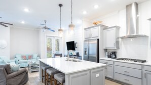 A modern kitchen with a central island, stainless steel appliances, and a dining area with a sofa and chairs. - Cozy 3bed townhome close to beach/step from Hub (Rosemary Beach)