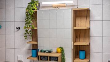 Un baño con espejo, estantes de madera y una planta en maceta.
