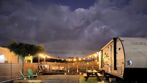 A campsite with RVs, a picnic table, and string lights. - Enjoy a cozy space in a RV Camper w/hot tub, near beaches. (Lajas)