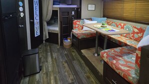 A compact, well-lit room with a bunk bed, a small table, and a sofa. - Enjoy a cozy space in a RV Camper w/hot tub, near beaches. (Lajas)