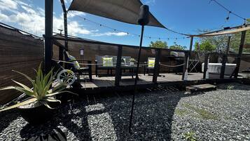Un patio con mobiliario exterior, una parrilla y una sombrilla grande que da sombra.
