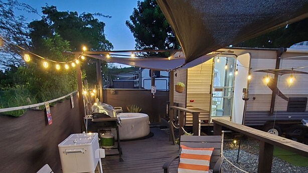 A deck with wooden benches and tables, string lights, and a hot tub. - Enjoy a cozy space in a RV Camper w/hot tub, near beaches. (Lajas)
