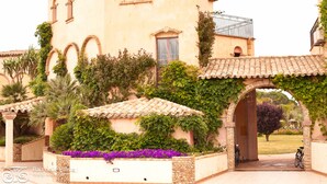 A building with arched windows and a tiled roof, surrounded by greenery and a brick pathway. - Baia Delle Palme Bilo Premium, Pula ( IT ), Italy (Pula ( IT ))