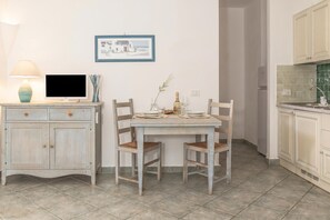 A dining area with a table set for two, a television, and a cabinet with drawers. - Palau Green Village Bilo, Palau, Italy (Palau)