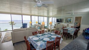 Un comedor con vista al océano, un ventilador de techo y un televisor.