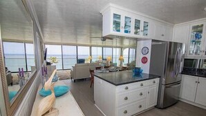 Una cocina moderna con una isla grande, armarios blancos y vistas al océano.