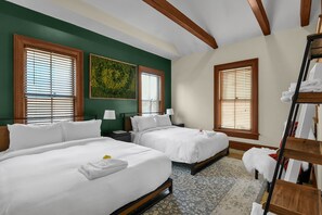 A hotel room with two beds, wooden headboards, and large windows with blinds.