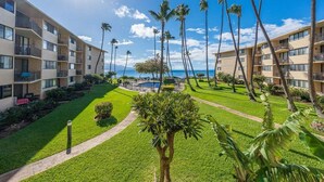 Un hotel de varios pisos, piscina al aire libre y palmeras.