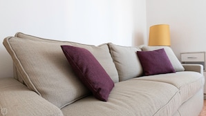A beige sofa with two purple cushions and a yellow lamp in the background. - Risorgimento 99 A in Sesto San Giovanni (Sesto San Giovanni)