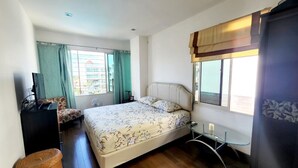 Un dormitorio con cama, escritorio, silla y ventana con cortinas.
