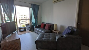 Una sala de estar con un sofá gris, un televisor y un mueble de madera.